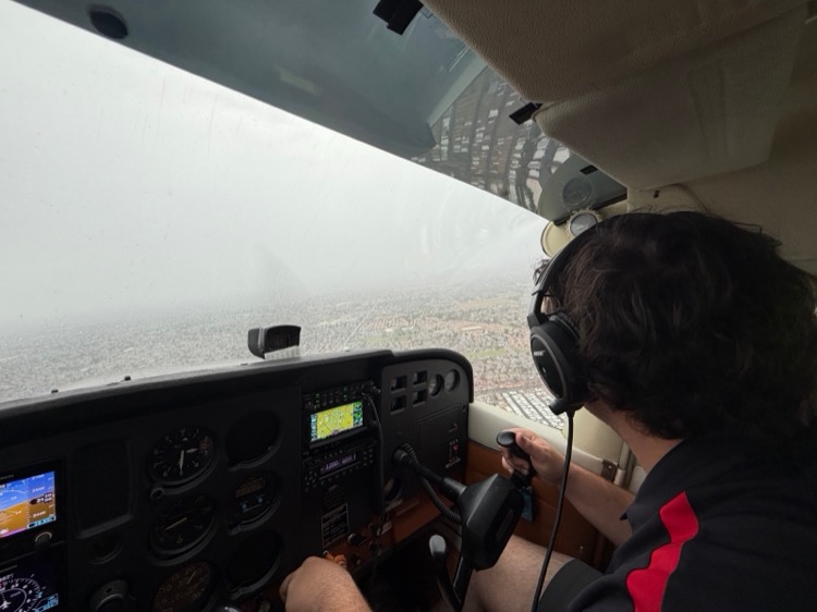 A pilot flying a Cessna 172 through rain and low visibility over Mesa, Arizona