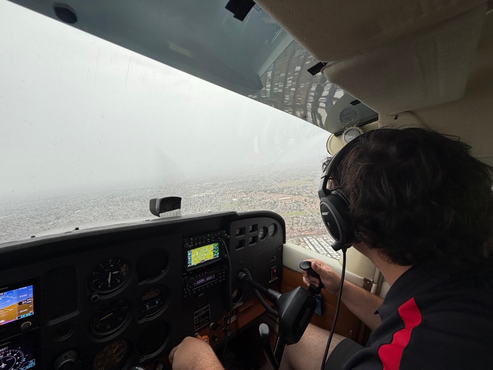 A pilot flying a Cessna 172 through rain and low visibility over Mesa, with the Garmin G5 and GPS lit on the panel